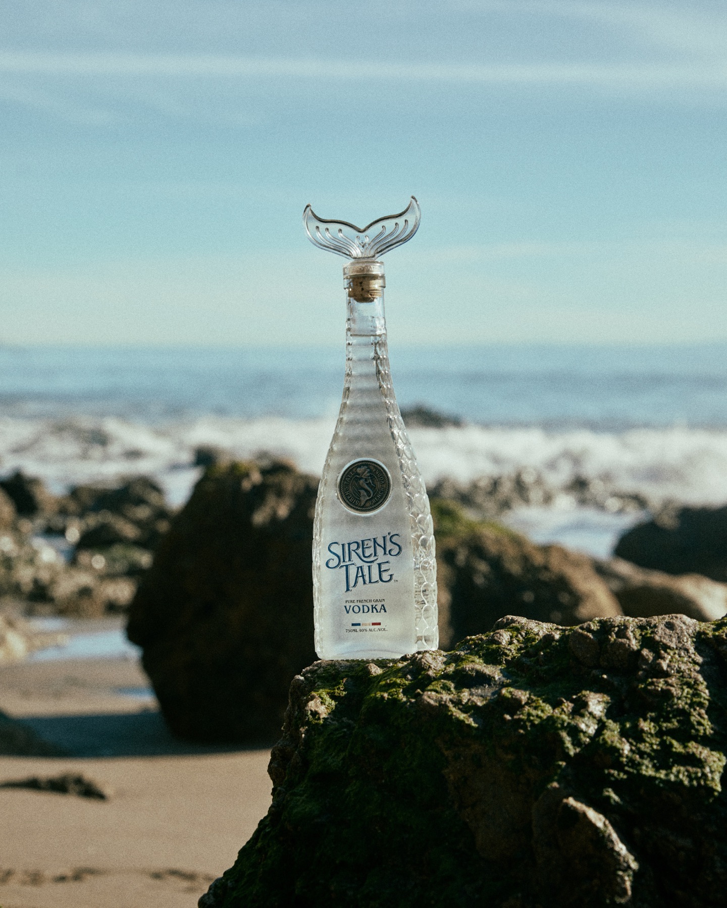 Siren's Tale Signature tail bottle on the rocks by the sea